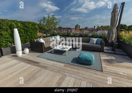 Luxuriöse Dachterrasse in London mit Schnittholz Terassendielen, zeitgenössische Pflanzmaschinen mit üppiger Bepflanzung und moderne Gartenmöbel Stockfoto