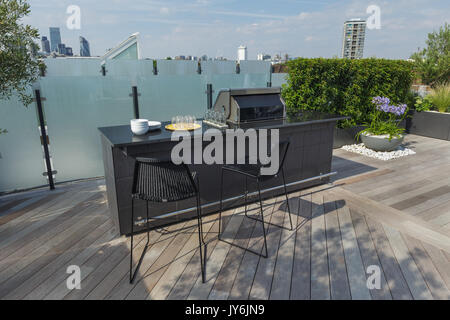 Luxuriöse Dachterrasse in London mit Schnittholz Terassendielen, zeitgenössische Pflanzmaschinen mit üppiger Bepflanzung und moderne Gartenmöbel Stockfoto