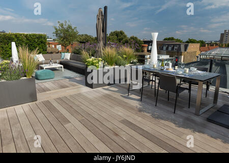 Luxuriöse Dachterrasse in London mit Schnittholz Terassendielen, zeitgenössische Pflanzmaschinen mit üppiger Bepflanzung und moderne Gartenmöbel Stockfoto