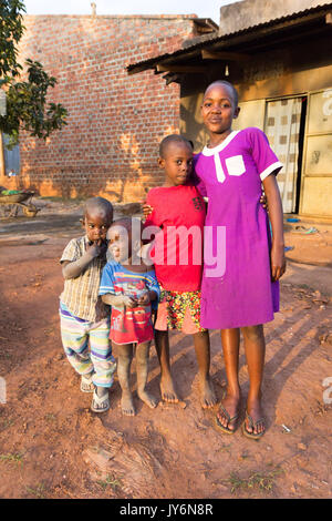 Eine Gruppe von smilng afrikanische Kinder, versteckt zusammen für ein Foto. Die Kinder vor einer einfachen hölzernen Schuppen sind, sind Sie Probabl Stockfoto