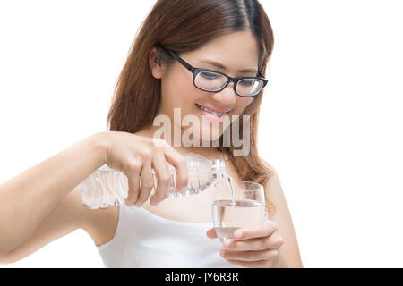 Junge Frau gießt Wasser in ein Glas isoliert auf weißem Stockfoto