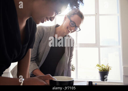 Zwei junge lächelnde Unternehmerinnen gemeinsam im Büro Stockfoto