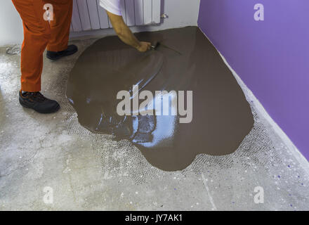 Apartment im Bau. Arbeitnehmer stellt ein fließestrich auf Zementboden Stockfoto