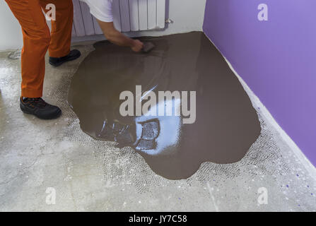 Apartment im Bau. Arbeitnehmer stellt ein fließestrich auf Zementboden Stockfoto