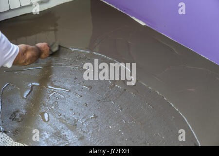 Apartment im Bau. Arbeitnehmer stellt ein fließestrich auf Zementboden Stockfoto