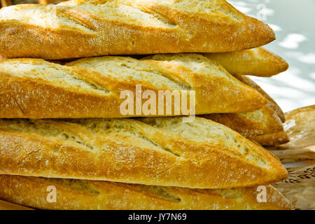 Bündel frisch gebackene rustikale französische Baguettes mit goldenen Kruste auf Garten Tisch outdoor Picknick Vorbereitung gestapelt. Sommer Sonnenlicht Flecken, Lifestyle Stockfoto