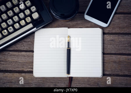 In der Nähe von Fountain pen auf Buch mit Schreibmaschine und Telefon am Tisch Stockfoto