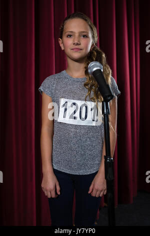 Stehendes Mädchen vor Mikrofon auf der Bühne im Theater Stockfoto