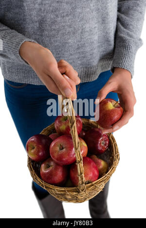 Den mittleren Abschnitt der Holding Korb mit Äpfeln, während gegen den weißen Hintergrund stehen Stockfoto