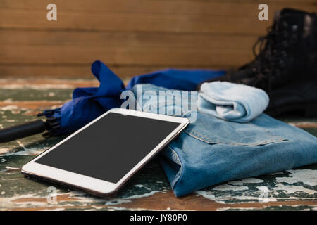 Nahaufnahme von Tablet Computer mit Jeans und Handschuhe von Dach auf hölzernen Tisch Stockfoto