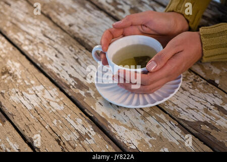 7/8 Hand der Frau mit Kaffee an den hölzernen Tisch Stockfoto