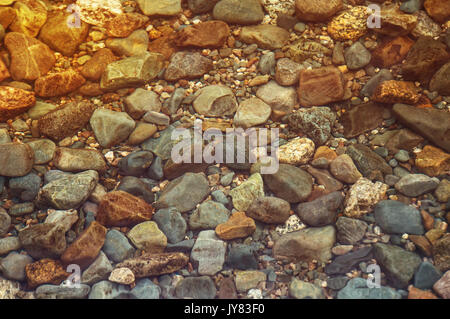 Hintergrund von Wasser und Stein. Bunte runde Steine unter Wasser Stockfoto