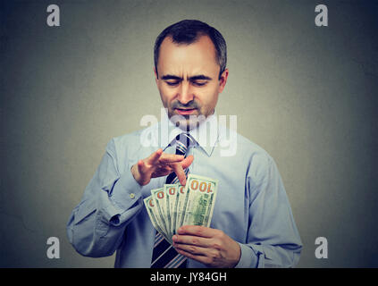 Ausgereifte Mann zählen Geld auf grauem Hintergrund Stockfoto