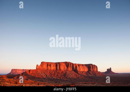 Monument Valley, Utah, USA. Warmen Morgenlicht hits Sentinel Mesa bei Sonnenaufgang. Stockfoto