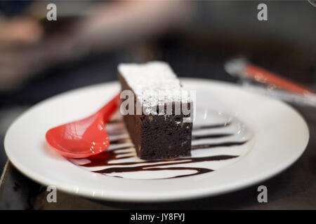 Brownies mit Schokolade mit roten Löffel auf dem Teller Stockfoto