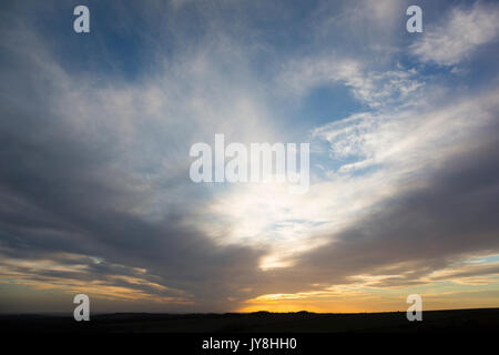 Ditchling Beacon, Sussex, UK. Wispy Wolken über einem tiefen orange Sonnenuntergang in Sussex. Stockfoto