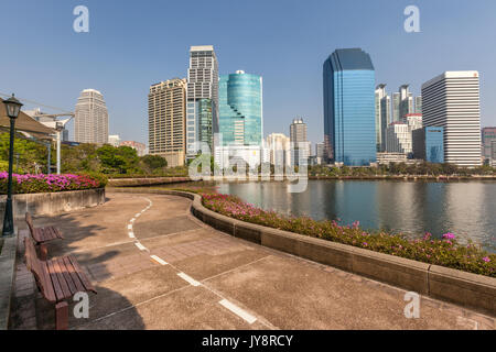 Benjakiti Park in Bangkok, Thailand Skyline mit Jogging Pfad um den See Ratchada, Bougainvilleas und Wolkenkratzer Stockfoto