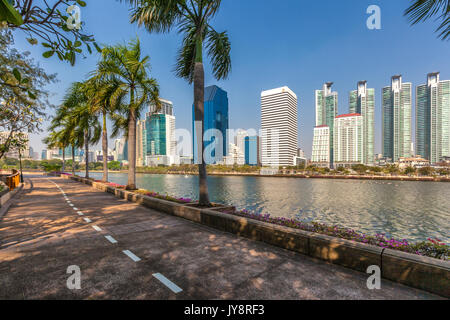 Benjakiti Park in Bangkok, Thailand Skyline mit Jogging Pfad um den See Ratchada, Bougainvilleas und Wolkenkratzer Stockfoto