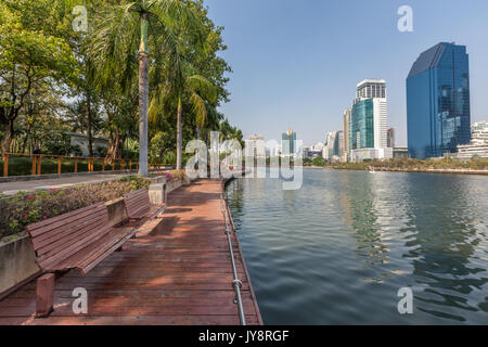 Benjakiti Park in Bangkok, Thailand Skyline mit dem hölzernen Promenade vor dem See Ratchada und Wolkenkratzer Stockfoto