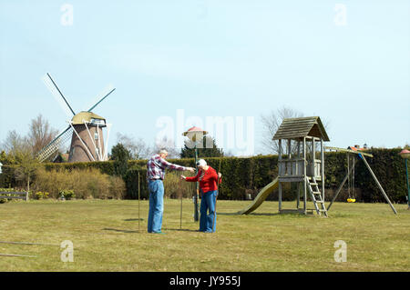 Ältere Paare versuchen, ein Zelt auf einem Campingplatz in der Neherlands mit einer Windmühle in den Hintergrund zu setzen Stockfoto