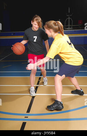 Zwei weibliche Basketball Spieler konkurrieren in der Turnhalle Stockfoto