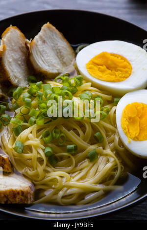 Japanische Ramen Suppe mit Hähnchen und gekochtem Ei in schwarz Schüssel Stockfoto