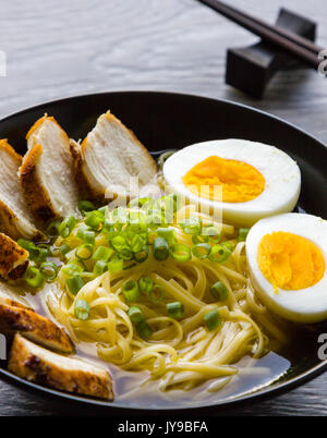 Japanische Ramen Suppe mit Hähnchen und gekochtem Ei in schwarz Schüssel Stockfoto