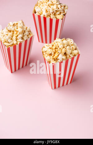 Popcorn in roten und weißen Karton auf rosa Hintergrund. Stockfoto