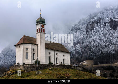 Die Kirche von Wassen an San Gottardo nach einer jüngsten Schneefälle, die Tannen hinter sich weiß geworden ist. andermatt. Kanton Uri, Schweiz. Europa Stockfoto