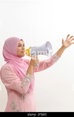 Malaiische Frau spricht in ein Megaphon eine öffentliche Ankündigung auf Weiß isoliert Stockfoto