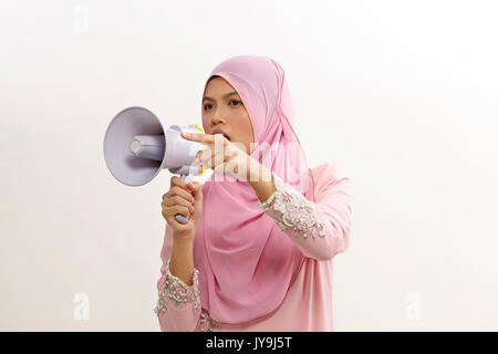 Malaiische Frau spricht in ein Megaphon eine öffentliche Ankündigung auf Weiß isoliert Stockfoto