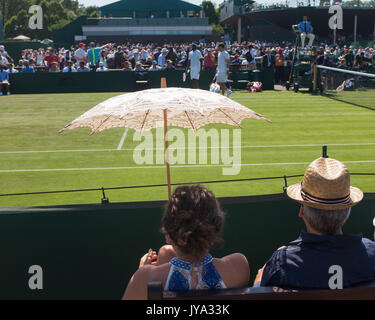 Zuschauer sitzt auf der Bank mit Regenschirm auf außerhalb des Gerichtes in Wimbledon Championships 2017, London, England, Vereinigtes Königreich. Stockfoto