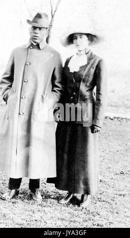 Afroamerikanischer Mann und Frau, die auf dem Rasen stehen und für ein Foto posieren, in kalter Kleidung, der Mann mit den Händen in der Tasche, Frau mit hellem Hautton, die einen breiten Hut trägt und neben ihm steht, 1932. Stockfoto