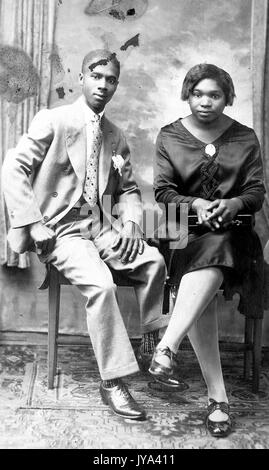 Junge afrikanische amerikanische Paar, ein Mann und eine Frau zusammen auf einer Bank sitzt, der Mann im Anzug, die Frau trägt ein Kleid und Lackschuhe, 1915. Stockfoto