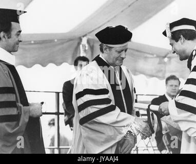 Steven Muller, Präsident der Johns Hopkins Universität, und Helmut Schmidt, der Bundeskanzler der Bundesrepublik Deutschland, Hände schütteln, während Muller Hände Schmidt einen Preis an den Zweihundertsten Einberufung an der Johns Hopkins University Homewood Campus, 16. Juli 1976 statt. Stockfoto