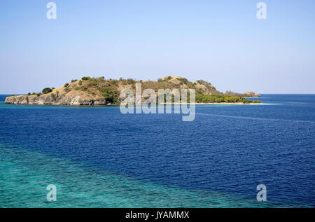 Kleine leere Rock Island mit grüner Vegetation im blauen Ozean Wasser in Labuan Bajo, Flores, Indonesien. Stockfoto