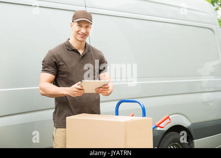 Junge glücklich Delivery Man mit digitalen Tablet und Kartons Stockfoto