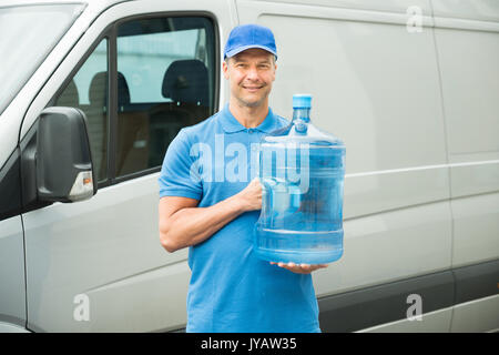 Happy Lieferung Mann hält die Flasche in der Vorderseite des Staplers Stockfoto