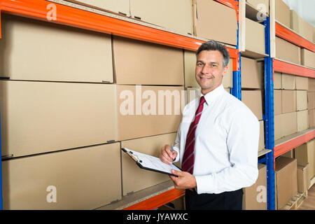 Gerne Manager Schreiben auf Zwischenablage im Versandlager Stockfoto