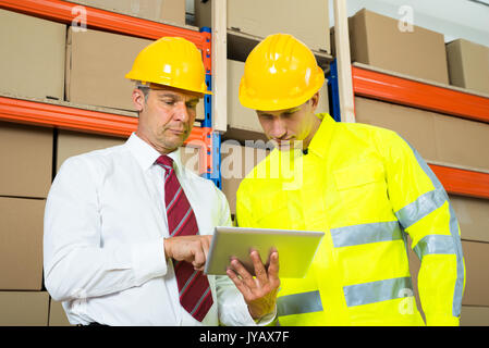 Lagerarbeiter und Manager am Laptop in ein großes Lager Stockfoto
