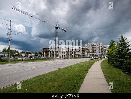 Gewitterwolken Ansatz Kran und Arbeiter auf dem Dach von Gebäude an einer Baustelle Stockfoto