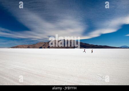 Zwei Menschen laufen auf der Oberfläche der Salar de Uyuni die größte Salzwüste der Welt. Süden Lipez. Bolivien. Südamerika Stockfoto