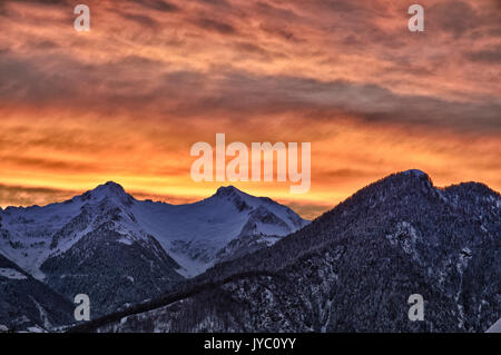 Ein Sonnenuntergang im Winter wärmt die Atmosphäre in Bitto Valley von albaredo nach einem starken Schneefall. Rasura. Valgerola. Bergamasker Alpen. Valtellina. In der Lombardei. Italien. Stockfoto