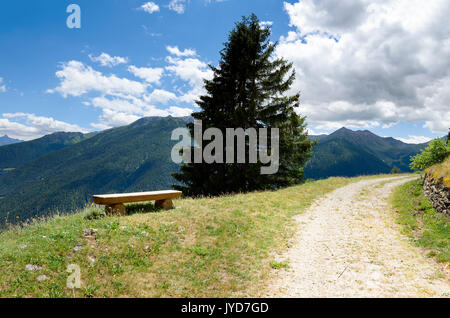 Sitzbank und eine geschwungene Landstraße in einer Berglandschaft Stockfoto