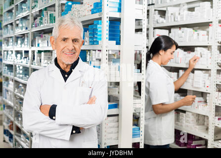 Leitender Apotheker stehen die Arme verschränkt, während Kollege prüfen Stockfoto