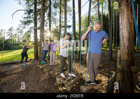 Business überqueren Swinging Logs im Wald Stockfoto