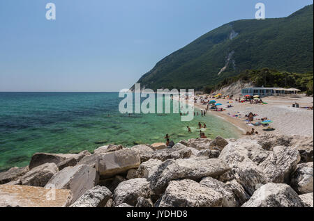 Touristen am Strand durch das türkisfarbene Meer Provinz Ancona Riviera del Conero Marche Italien Europa gerahmt Stockfoto