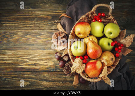 Korb mit frischen Äpfeln und Birnen auf einem Holztisch. Herbst Hintergrund. Stockfoto