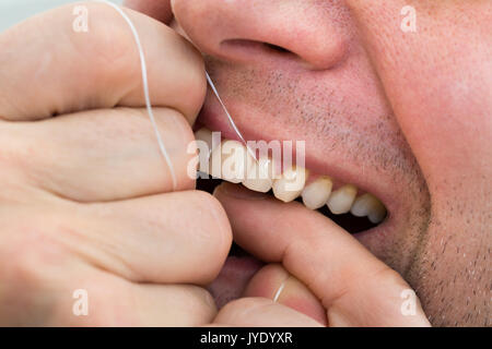 Nahaufnahme eines Mannes Flossing seine Zähne Stockfoto