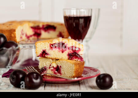 Hausgemachte Pflaumenkuchen auf einem Standfuß aus Glas und Rotwein. Selektive konzentrieren. Stockfoto